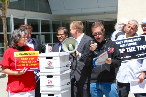 EFF's Jeremy Malcolm speaking at a street rally outside Leader Pelosi's office. Photo by Kate Usher. Jeremy Malcolm speaking into a microphone at a street rally